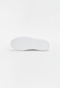 Biała podeszwa sneakerów z teksturowanym wzorem, z poziomymi i pionowymi rowkami zapewniającymi przyczepność oraz zaokrąglonym noskiem.
