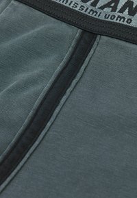 Herrens kalsonger i mörkgrått tyg med en mjuk yta, med ett svart elastiskt midjeband och kontrasterande sömdetaljer.