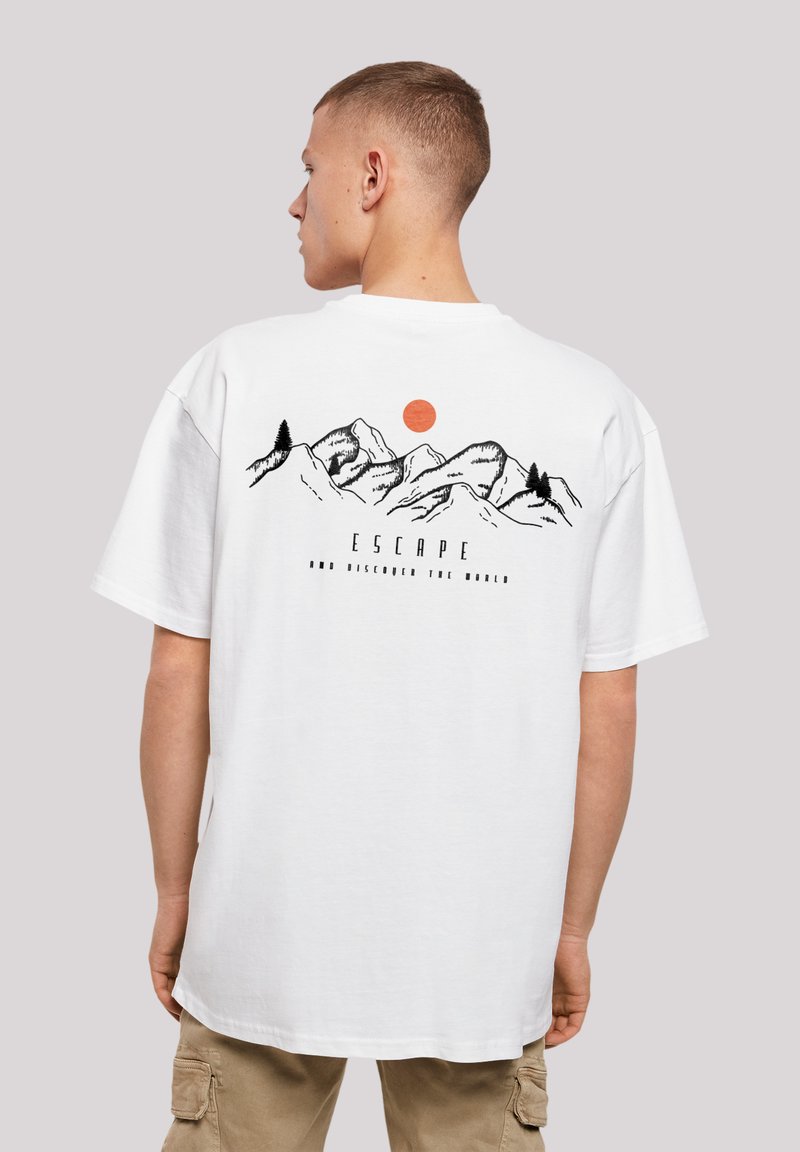 White cotton t-shirt with a mountain graphic, black outlines, a red sun, and text "ESCAPE AND DISCOVER THE WORLD" on the back.