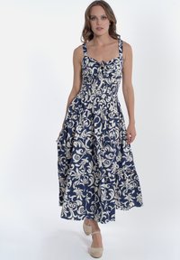 Abito midi blu navy con motivo floreale bianco, scollatura quadrata e spalline regolabili. Presenta vita arricciata e gonna svasata.