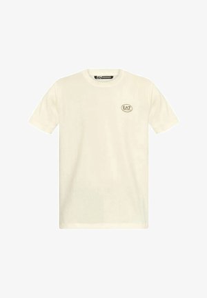 T-shirt a maniche corte color crema in cotone, con scollatura rotonda e un piccolo logo EA7 in beige sul petto sinistro.