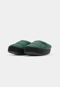 Green padded slippers with a textured black rubber sole, featuring a low profile and a comfortable shape for indoor use.