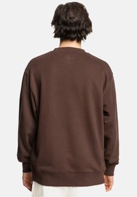 Bruine sweatshirt met een losse pasvorm en lange mouwen. Kenmerkt zich door een geribbelde zoom en manchetten, gemaakt van zachte, textuurstof. Eenvoudig ontwerp zonder patronen.