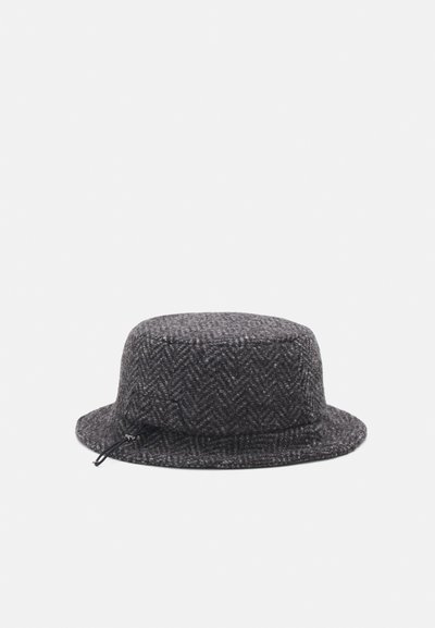 Grå herringbone ullhatt med flat krone og bred, sydd kant; har snor for størrelsesjustering.