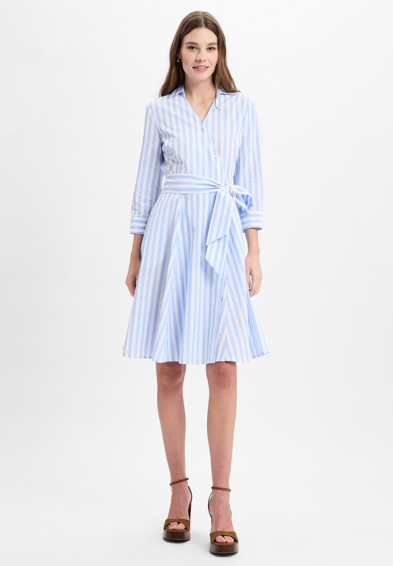 Button-up dress with vertical light blue and white stripes. Features a tied waist belt, long sleeves, and a flared skirt.