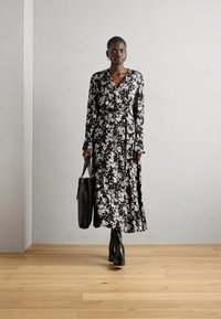 Crna cvjetna haljina s dugim rukavima, strukirana i s lepršavom suknjom. Dopunjena crnom torbom i čizmama do gležnja.