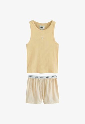 Beige geribde tanktop met wit "self." label en bijpassende shorts met elastische tailleband met herhalende "self." tekst.