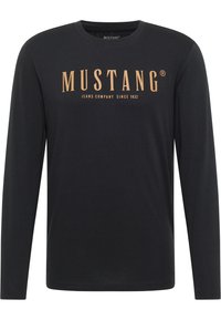 Zwart lange mouw t-shirt van katoen met een ronde hals. Heeft een grote, gouden print op de voorkant met de tekst "MUSTANG JEANS COMPANY SINCE 1932".