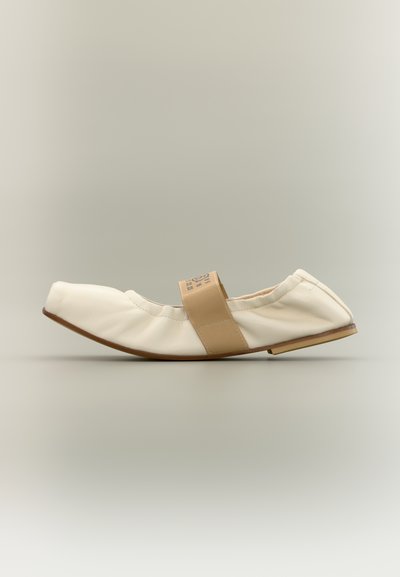 Ballerine en cuir souple beige avec une bride élastique beige sur le dessus, bout carré et semelle plate, vue de profil sur un fond neutre.