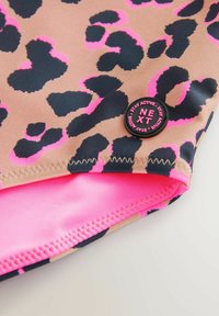 Leopardenmusterstoff in Beige mit schwarzen und pinken Akzenten. Verfügt über ein pinkes Innenfutter und ein schwarzes rundes Etikett mit dem Text "NEXT".