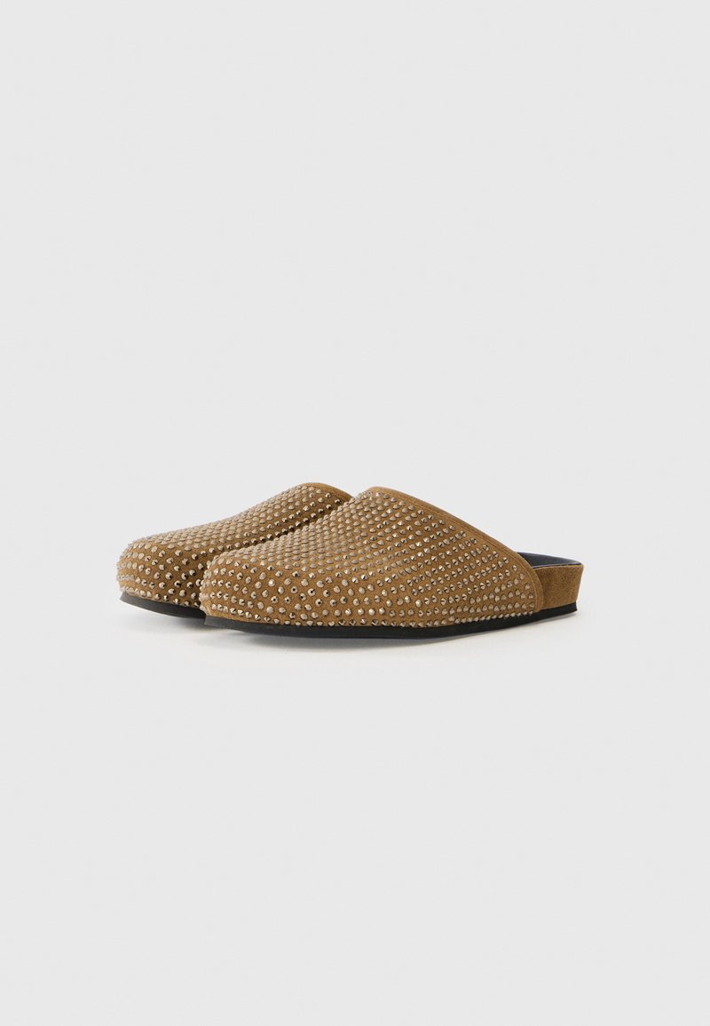Braune Wildlederschuhe mit geprägtem Muster, abgerundeter Zehenpartie und glattem Innenbereich. Die Sohle ist schwarz und hat ein flaches Profil.