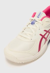 Weißer Sportschuh mit rosa Akzenten, Mesh-Obermaterial, strukturierten Einsätzen und einer weißen Gummisohle. Mit markierten Schnürsenkeln und Zungen-Details.