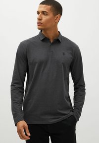 Langärmliges Poloshirt aus dunklem grauen Baumwollstoff mit einem dezenten Emblem auf der Brust, klassischem Kragen und geradem Saum.