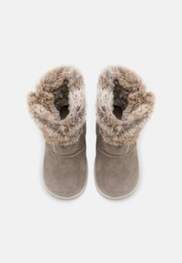 Bottines en suede marron avec une bordure en fausse fourrure en haut. Forme de nez arrondi et semelle en caoutchouc. Détails cousus le long de la tige.