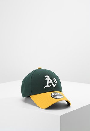 Cappello da baseball verde con visiera gialla, con il logo ricamato bianco "A's" sul davanti e un adesivo decorativo sulla visiera.