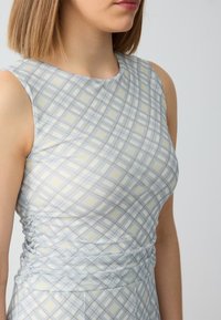 Hellblaues ärmelloses Kleid mit karriertem Muster in Beige und hellgrauen Akzenten, strukturiertem seitlichen Raffung und rundem Ausschnitt.