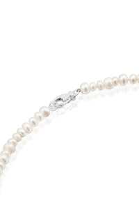 Collana di perle bianche con perle ovali e rotonde di diverse dimensioni, chiusa con un fermaglio a forma di granchio in argento. Texture liscia e lucida.