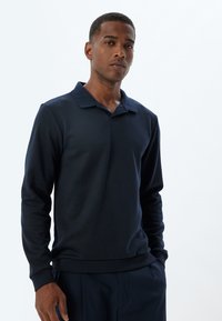 Navyblaues Langarmpoloshirt aus weichem Material. Mit Kragen und gerippten Bündchen. Schlichtes, unverziertes Design.