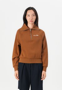 Brown zip-neck pullover sweatshirt with ribbed cuffs and hem. Features logo embroidery on the chest and a structured collar design.