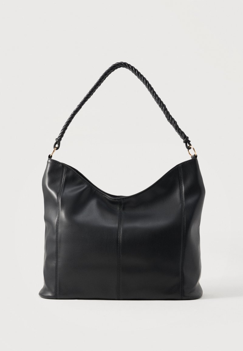 Sac à épaule en cuir noir avec poignée torsadée et détails de couture verticale sur un fond clair uni.