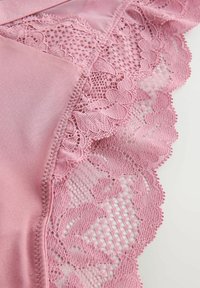 Roze lingerie met een zachte satijnen afwerking en delicate bloemenkant rand. Heeft gegolfde randen en ingewikkelde patronen op het kant.