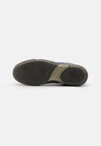 Black rubber shoe sole with textured grip patterns; features a translucent heel section and a gray accent near the center.