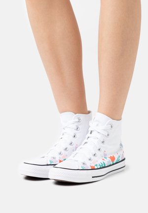 Witte canvas sneakers met hoge schacht en bloemenprintaccenten in roze en groen. Voorzien van zilveren oogjes en een zwarte rubberen zool.