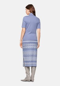 Blue dress with short sleeves, featuring a patterned lower section in blue and white hues, paired with knee-high gray boots.