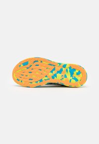 Semelle de basket multicolore brillante avec des motifs orange, bleu et jaune, avec une adhérence texturée et des trous de ventilation.