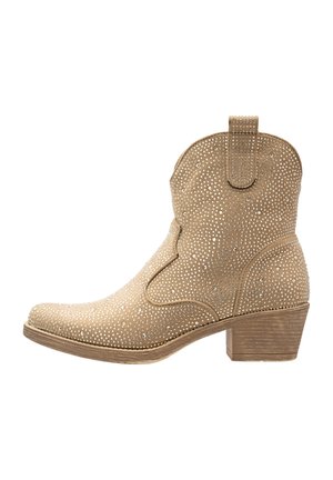 Beige cowboylaarzen met een gestructureerde suède afwerking, versierd met zilveren rhinestones, een spitse neus en een lage houten hak.