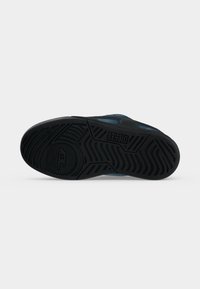 Semelle d'une basket bleue avec une bande de roulement en caoutchouc noir, portant la marque Diesel et des motifs de grip géométriques.