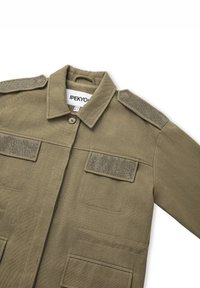 Chaqueta caqui con cierre de botón, dos bolsillos frontales con solapa y parches en los hombros. Confeccionada en tejido texturizado, presenta un cuello y mangas largas.