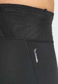 Black athletic leggings with a flat waistband, featuring a ClimaCool logo, smooth texture, and decorative stitching along the seams.