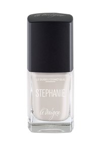 Nagellack in einer klaren Glasflasche mit quadratischem Boden, ausgestattet mit einem schwarzen, schrägen Deckel. Der Lack hat eine sanfte, neutrale Beigetönung.