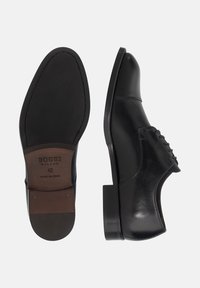 Mustad mustast nahast kleitkingad, millel on sile viimistlus, nööbiproovimise disain, kitsas kuju ja kihiline konts. Suurus 42, pruuni sisetalla sildiga.