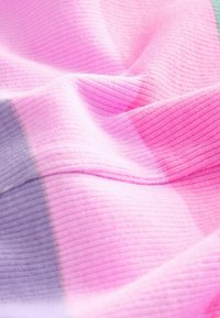 Tkanina iz pletenih vlaken v različnih odtenkih roza in sivke, z ribano teksturo in gladkim zaključkom, ki prikazuje mehke, tekoče drape.