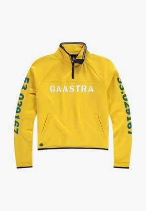 Žlutý fleecový pulovr s límečkem na čtvrtiny zipu, s bílým nápisem „GAASTRA“ a tyrkysovými čísly na rukávech, boční kapsou a tmavě modrými akcenty.
