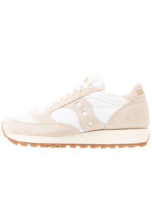 Beige en witte sneaker met een bovenwerk van suède en mesh, met een ronde neus, vetersluiting en een opvallend logo aan de zijkant met een gumrubberen zool.