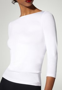 Weißes Oberteil mit drei Viertelärmeln und Bootsausschnitt, glatte Textur, figurbetontes Design und kontrastierendes schwarzes Taillenband darunter.