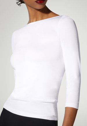 Top bianco a maniche tre quarti con scollo a barca, texture liscia, design aderente e vita nera a contrasto sottostante.