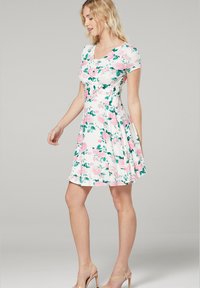 Short-sleeve, fit-and-flare dress made of white fabric with pink rose and green leaf patterns. Knee-length, with a smooth texture and subtle pleats.