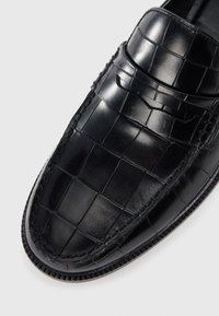 Pantofi negri din piele cu model în relief de crocodil, lucioși, cu vârful rotunjit și accente cusute contrastante pe talpă.