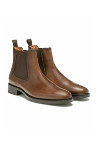 Bottines Chelsea en cuir marron avec des côtés élastiques, bout rond et talon bas empilé. L'intérieur présente une doublure orange contrastante.