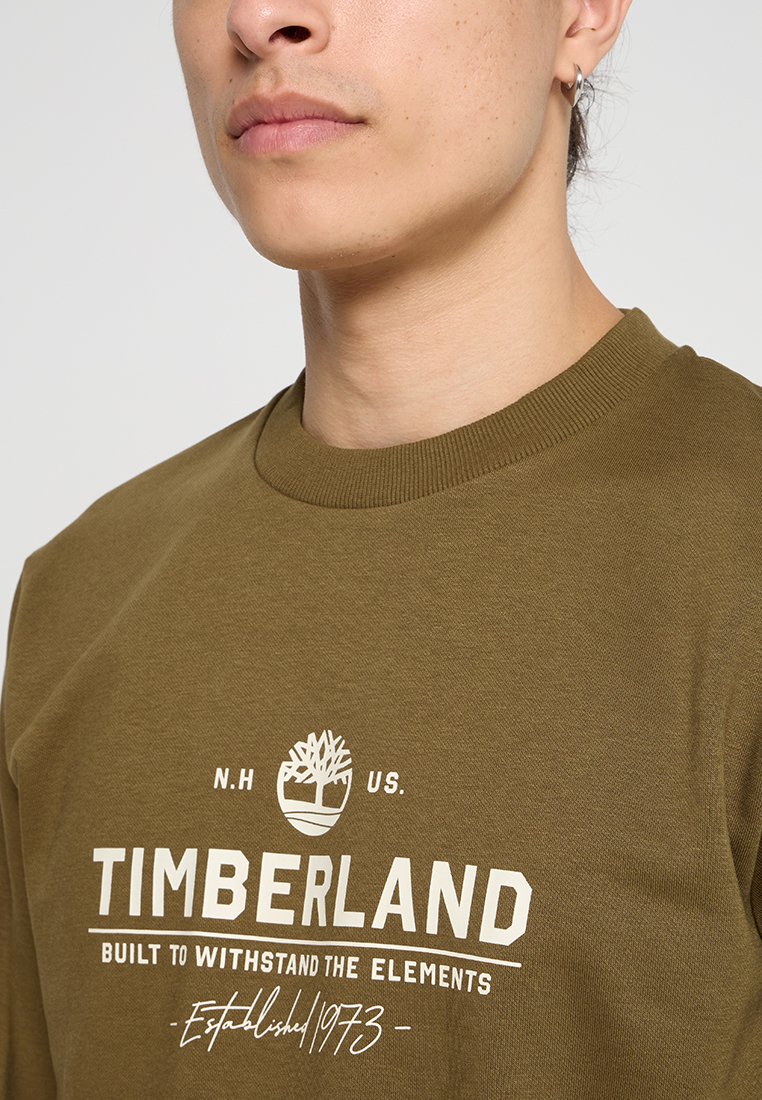 Felpa verde khaki in cotone, con colletto tondo e il logo "Timberland" in testo bianco con una grafica di un albero.
