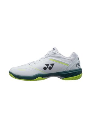 Witte en groene lage sportschoen met zwart logo aan de zijkant en neongele accenten, ontworpen voor gebruik op binnenbanen.