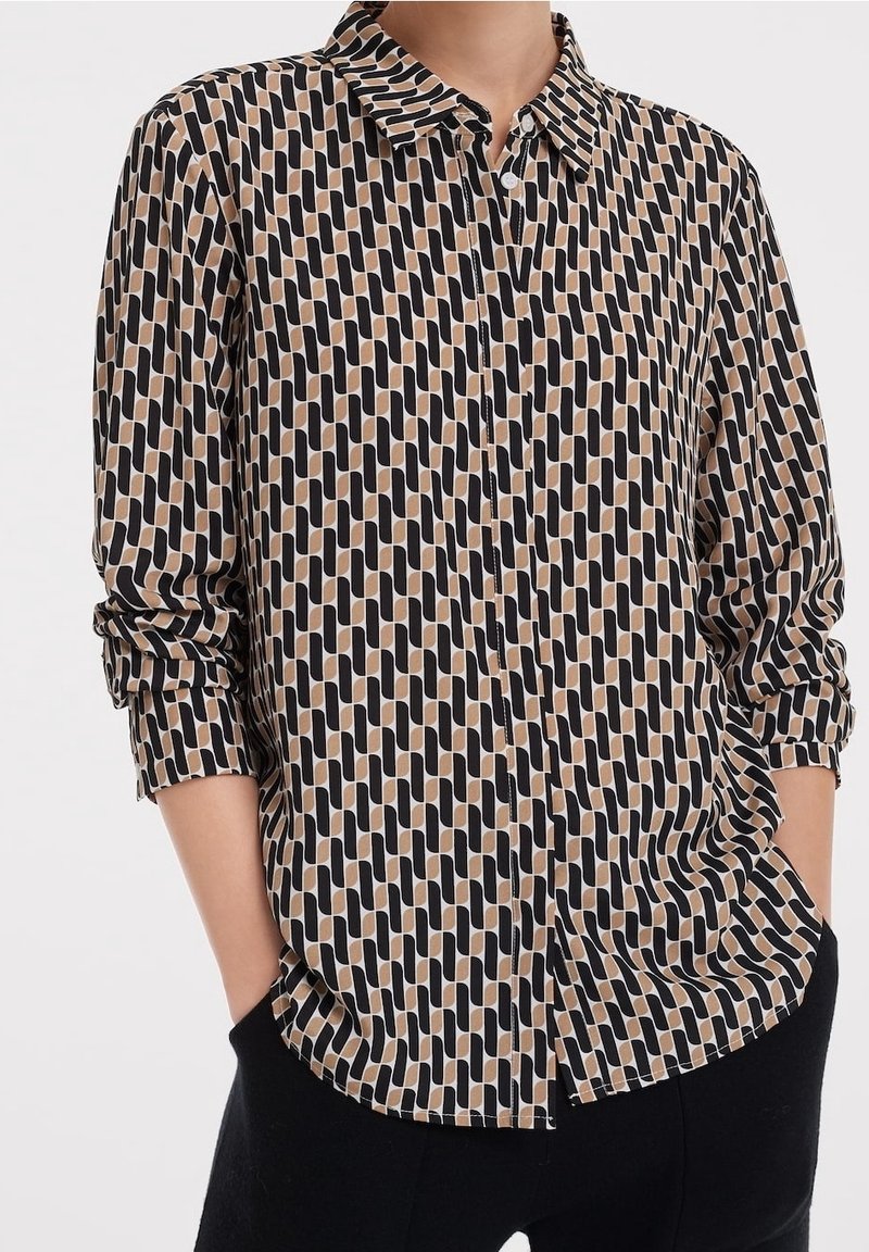Camicia a maniche lunghe in un tessuto leggero con un motivo geometrico nei colori nero, marrone e crema, con colletto a punta e bottoni.