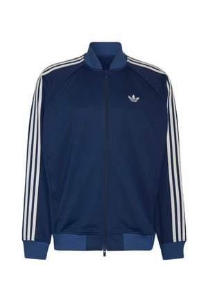 Marineblaue Trainingsjacke mit Reißverschluss und weißen drei Streifen auf den Ärmeln sowie kleinem weißen Adidas-Logo auf der linken Brust.