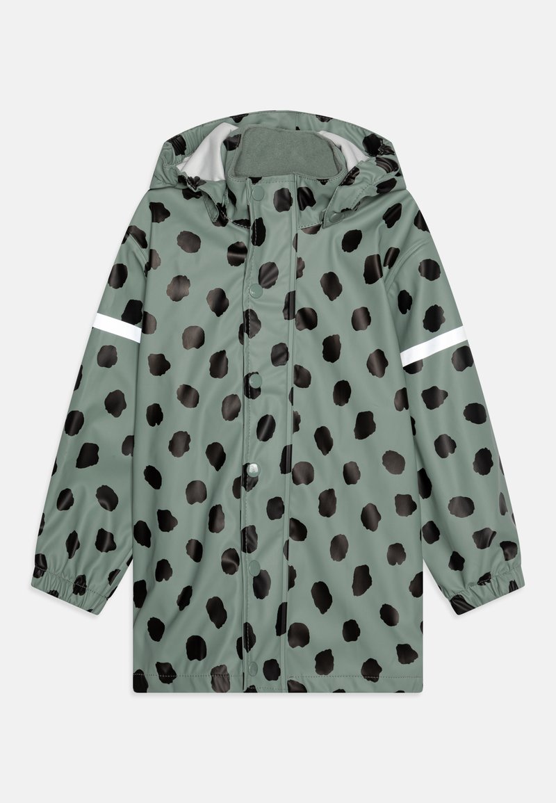 Veste imperméable verte avec des pois noirs irréguliers. Équipée d'une capuche, de boutons-pression, de poignets élastiques et d'une bande réfléchissante sur la manche.