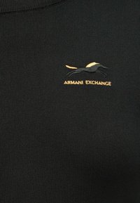 Sweater preto tricotado com um design ajustado. Apresenta um logótipo bordado em ouro e preto de um cavalo e o texto "ARMANI EXCHANGE."