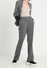 Šedý texturovaný blazer spárovaný se šedými tailored kalhotami. Sako má černé detaily na rukávech. Černé sneakers dokončují vzhled.
